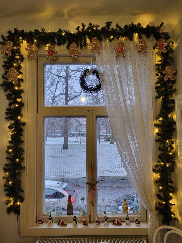 Winters uitzicht vanuit een café op besneeuwde bomen en een krans