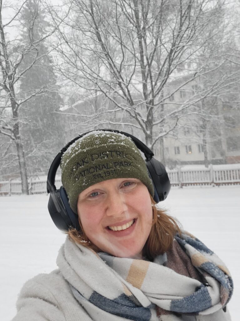 Genieten van de sneeuw in een groene muts, koptelefoon en sjaal