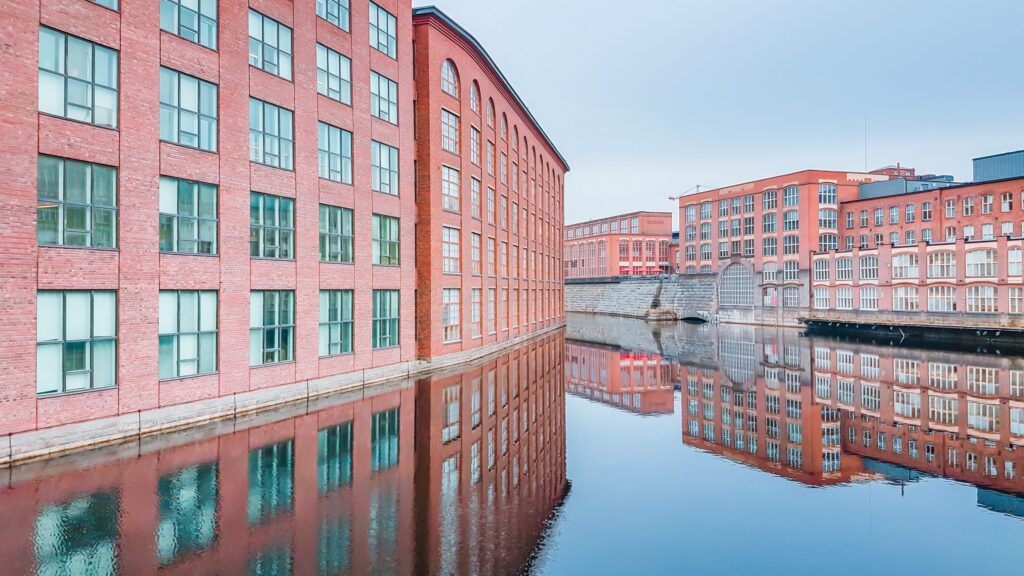 De oude fabrieksgebouwen, met kenmerkende rode stenen, weerspiegeld in water