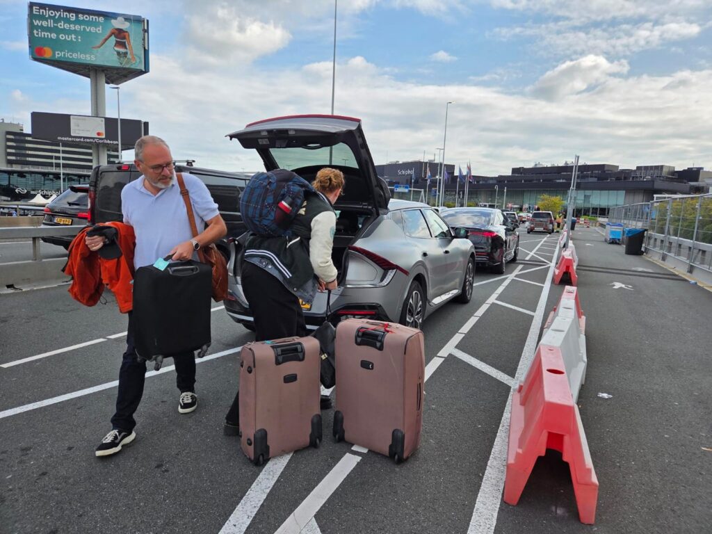Vader en dochter pakken hun koffers uit de auto op het vliegveld